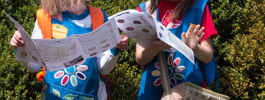 Two Girl Scouts with Daisy uniforms mulling over garden maps