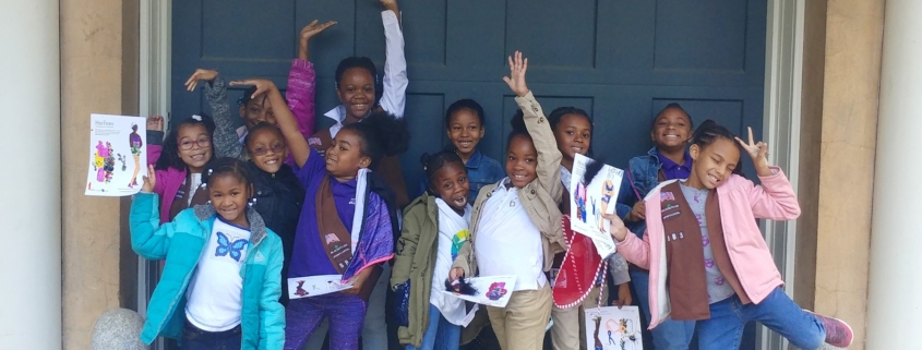 Bunch of Girl Scout Browns posing for the camera with big smiles and holding up examples of their craft project.