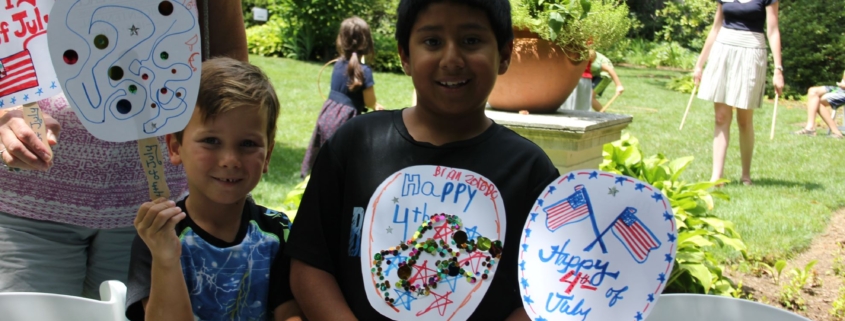 Couple kits holding up hand made July 4 fans made from paper plates