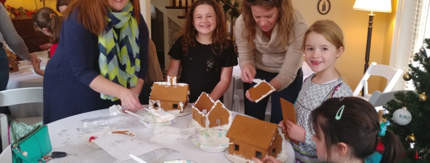 Mothers with children actively building gingerbread house