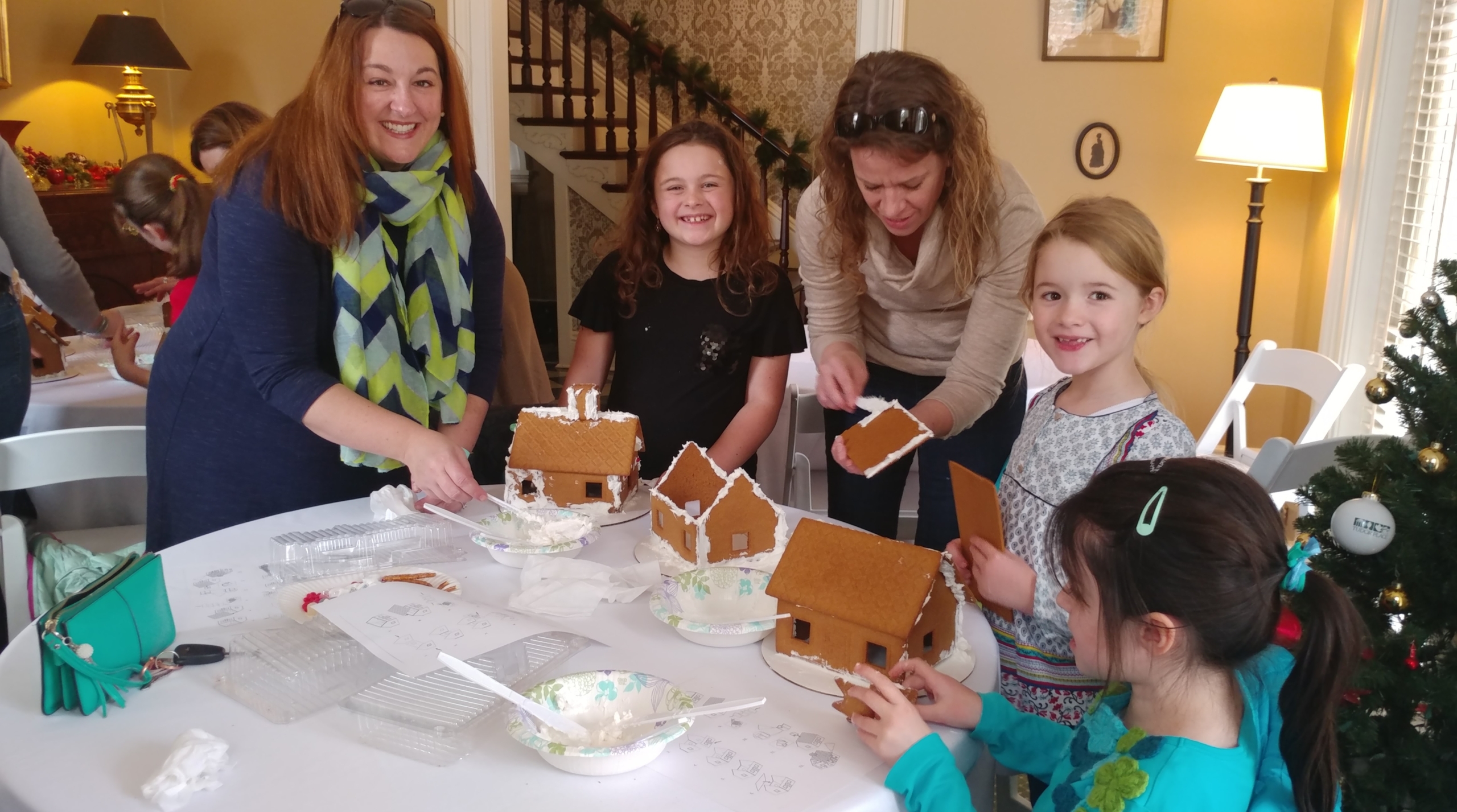Mothers with children actively building gingerbread house