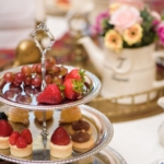 Two tiered dessert tray with fruit and sweets.