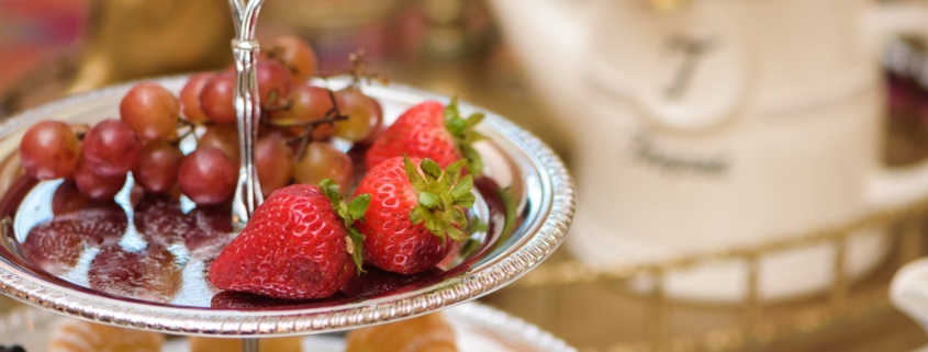 Two tiered dessert tray with fruit and sweets.