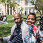 Close up of man and woman sitting on blanket enjoying sunshine at outdoor venue